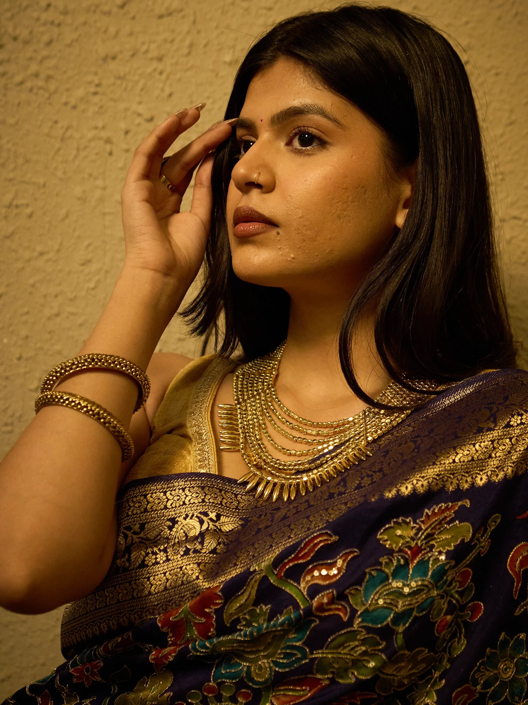 Full-length styled drape of blue soft silk Kalamkari saree with gold Zardozi border, worn with gold jewellery for Indian wedding